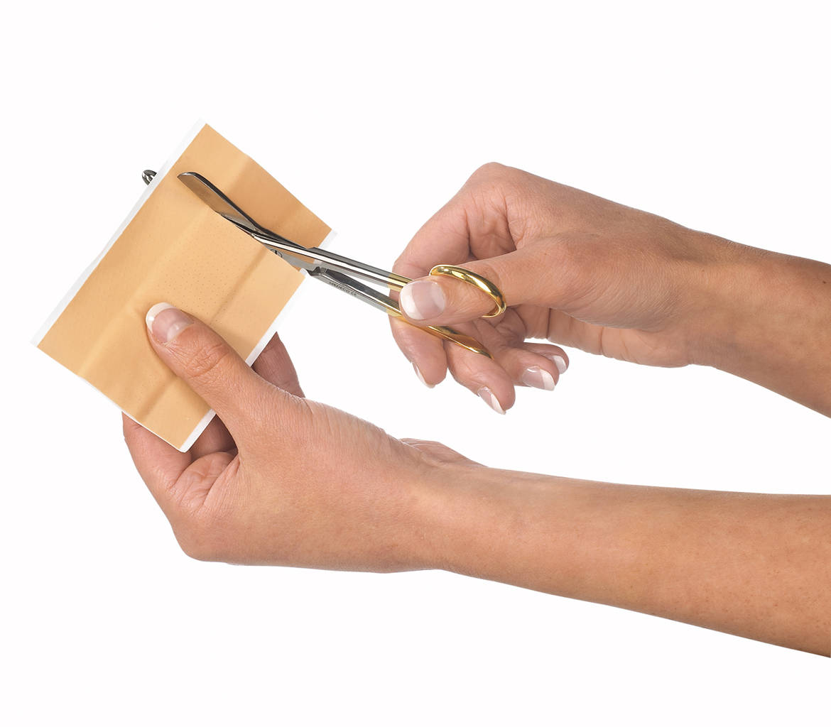 Hands cutting plaster with scissors