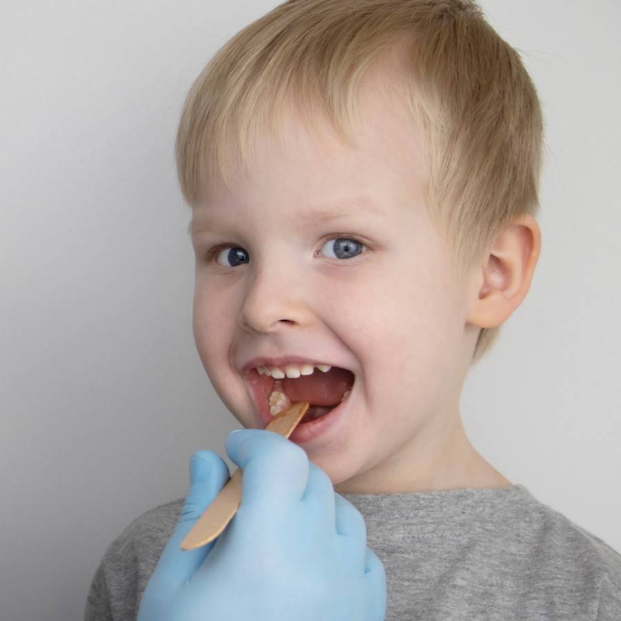 Young child with wooden spatula in mouth