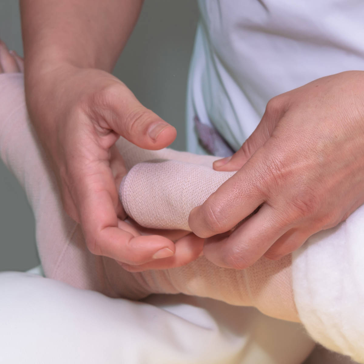 Hands putting compression bandage on ankle